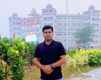 Mishra in front of building bushes